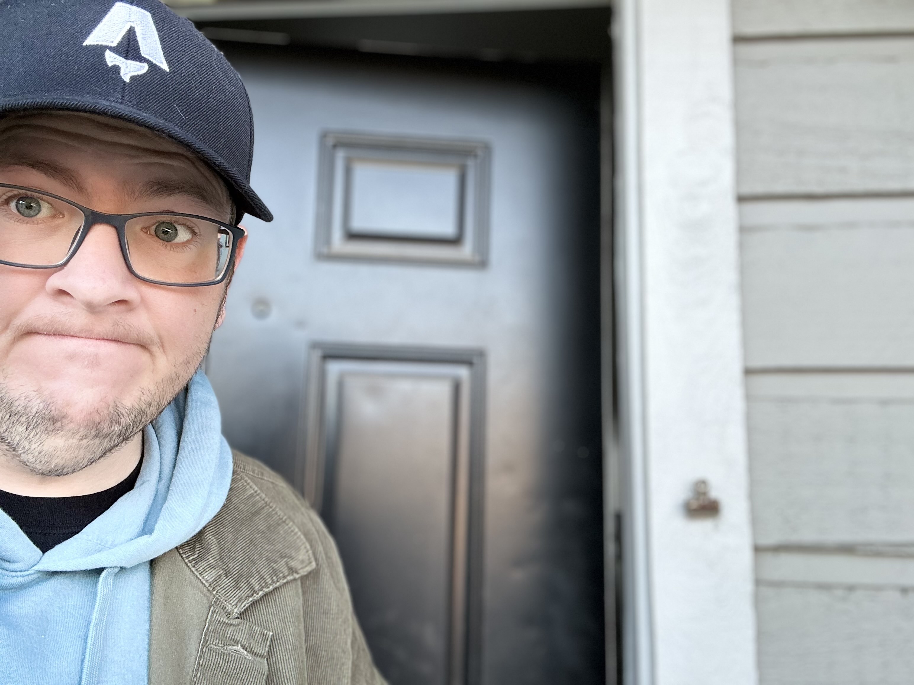A picture of me, Michael. I am wearing a hat and walking out of a my apartment.